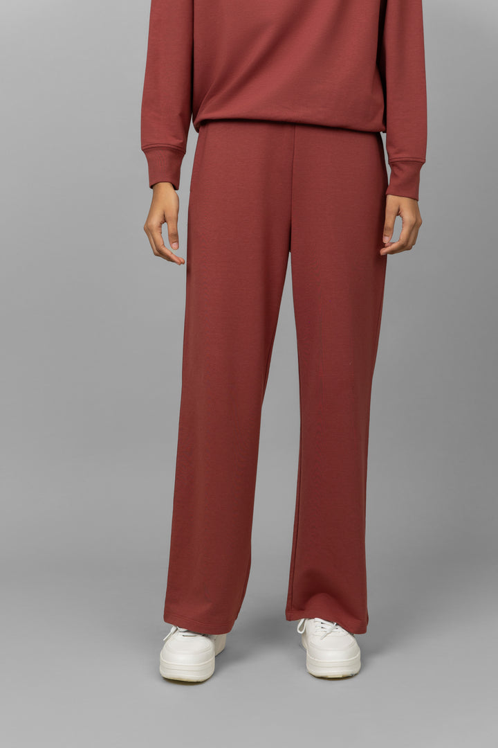Rust Travel Bamboo Terry Pant with relaxed fit and white sneakers.