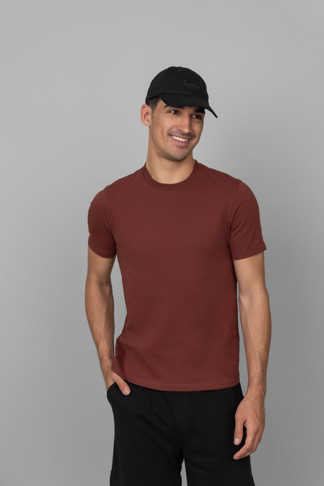 Men's rust shorts set model wearing casual outfit with black cap.