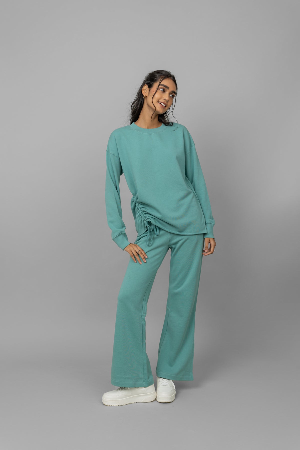 Model wearing a teal cotton terry sweatshirt and matching pants.