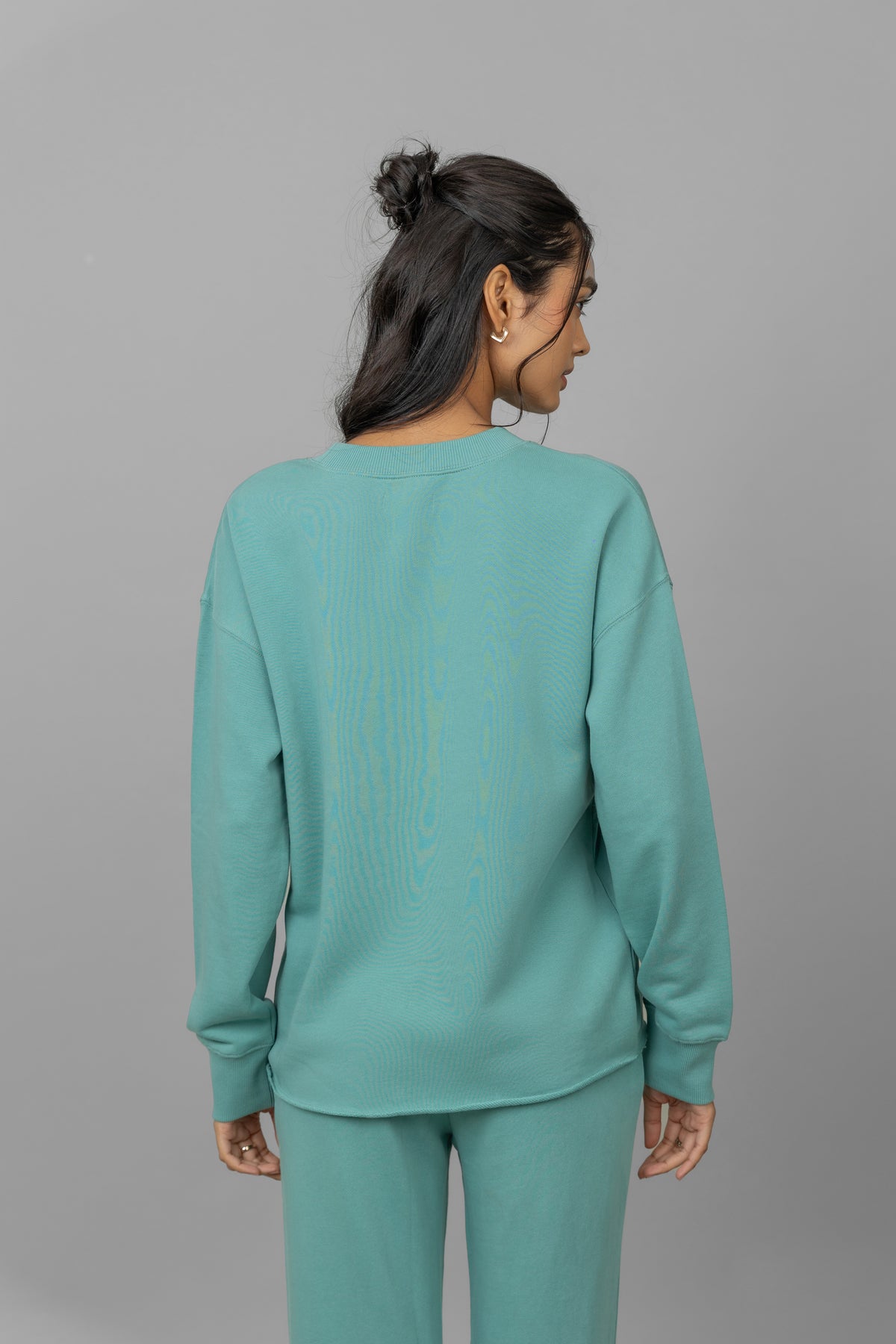 Model wearing a teal Cotton Terry Sweatshirt, back view.