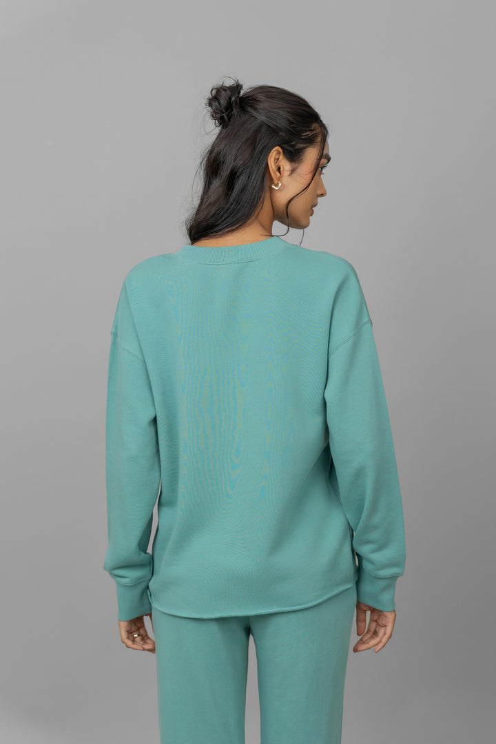 Model wearing a teal Cotton Terry Sweatshirt, back view.