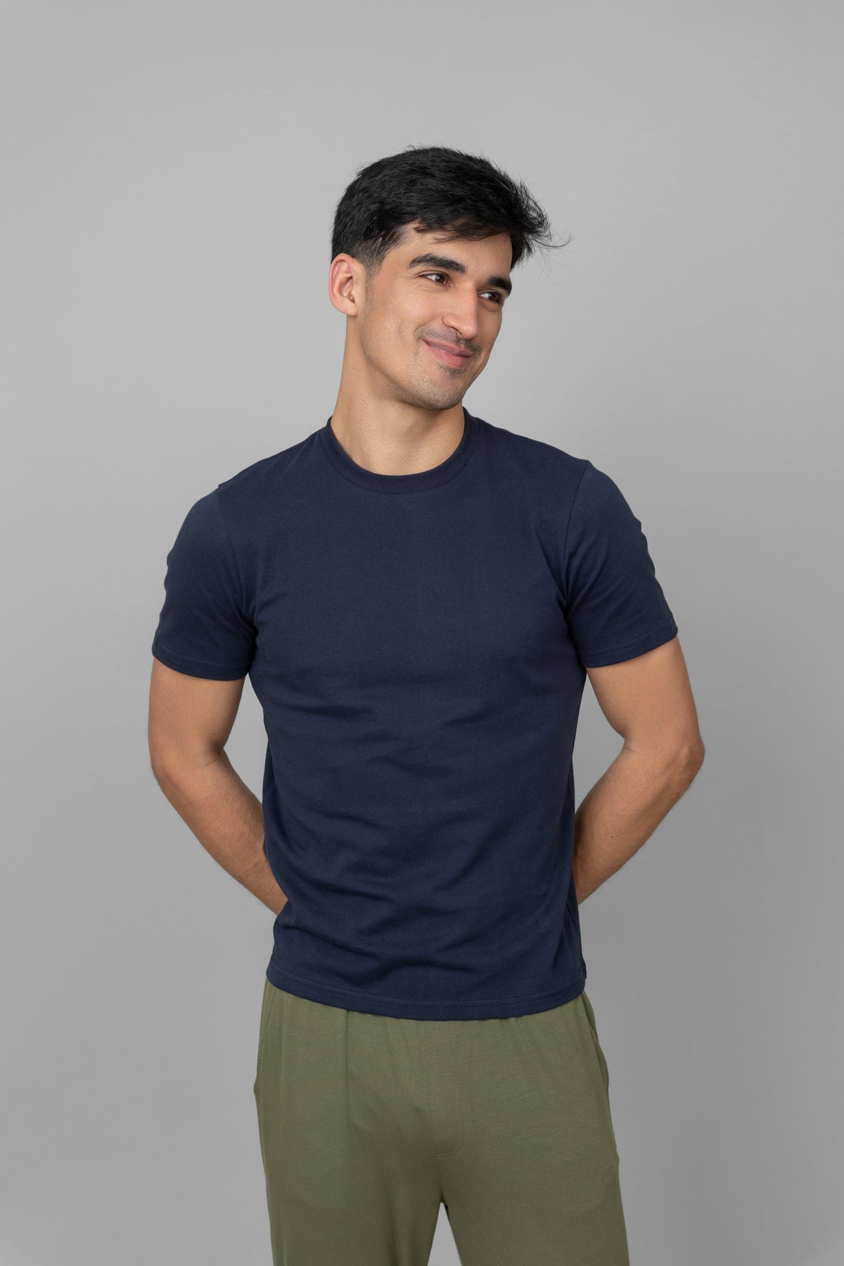 Navy men's essential t-shirt worn by smiling man against gray backdrop.