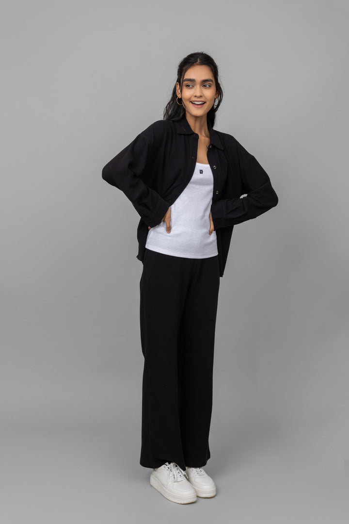 Black mini waffle pajama set modeled by woman in relaxed pose.