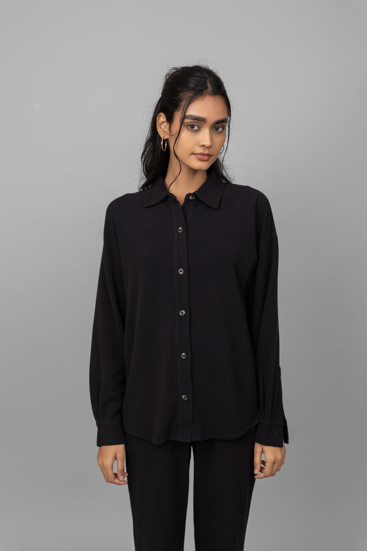 Black mini waffle pajama set worn by model on gray background.
