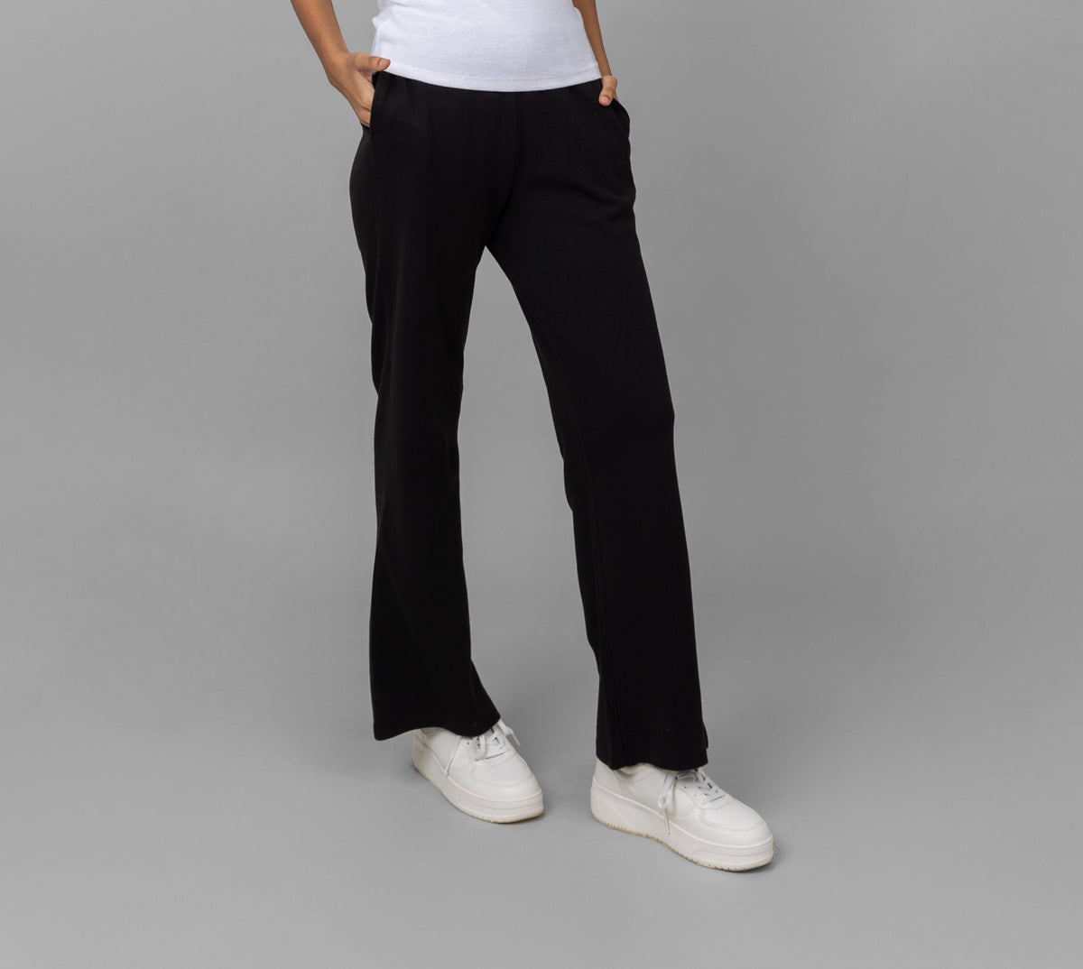 Black Mini Waffle MultiTask Pants modeled with white sneakers on gray background.