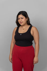 Black rib tank top paired with red pants on model.
