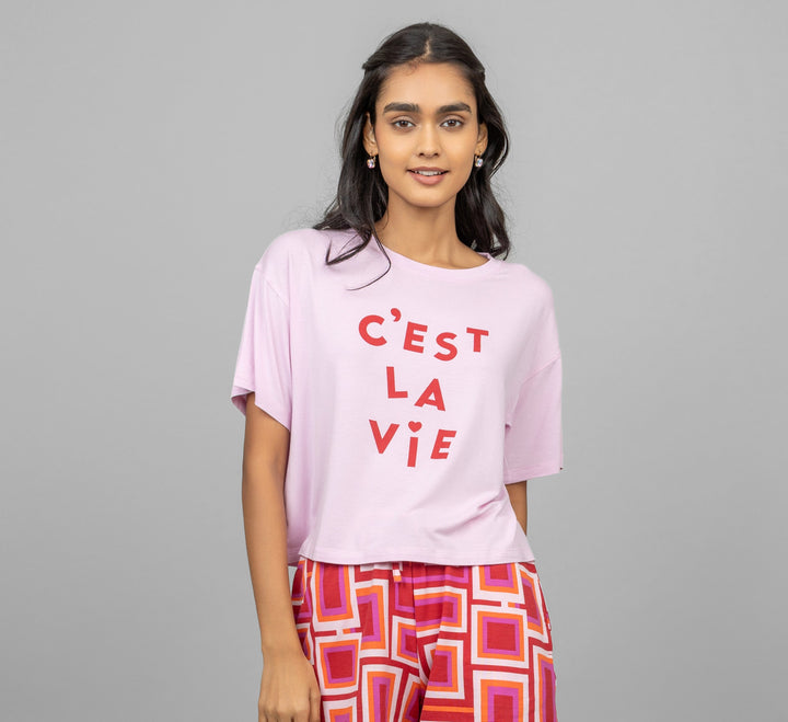 C'est La Vie pink crop top worn by model with stylish pants.