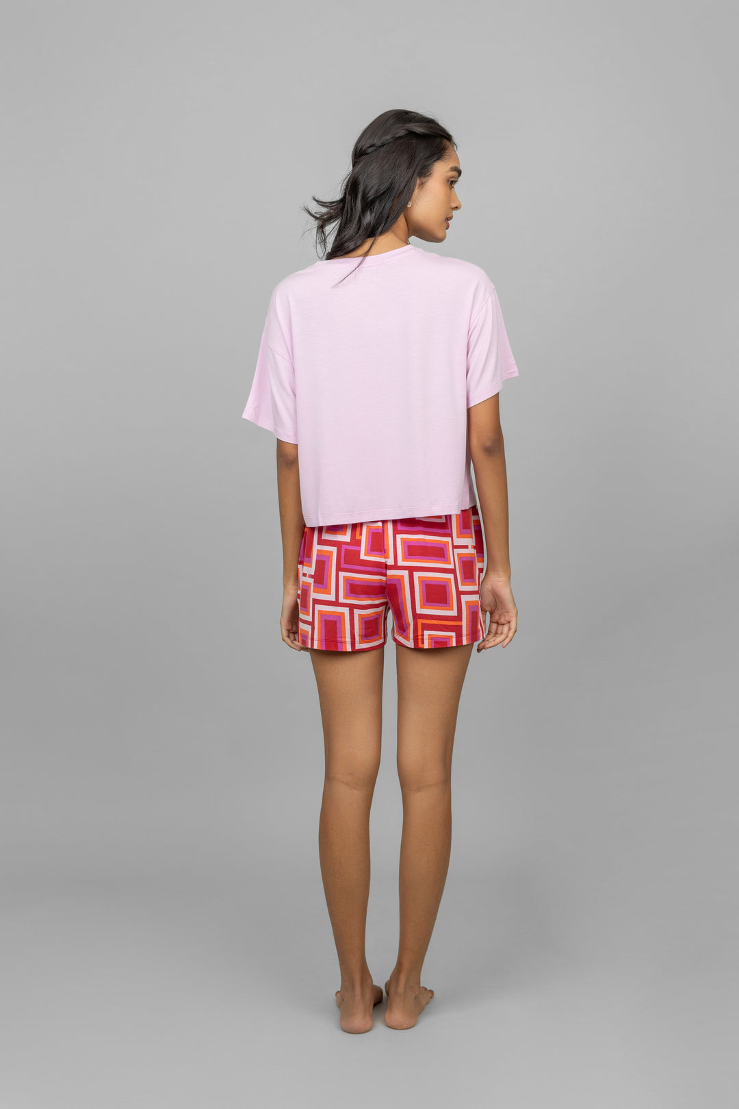 Model wearing Red Zen Shorts with pink top, showcasing stylish back view.
