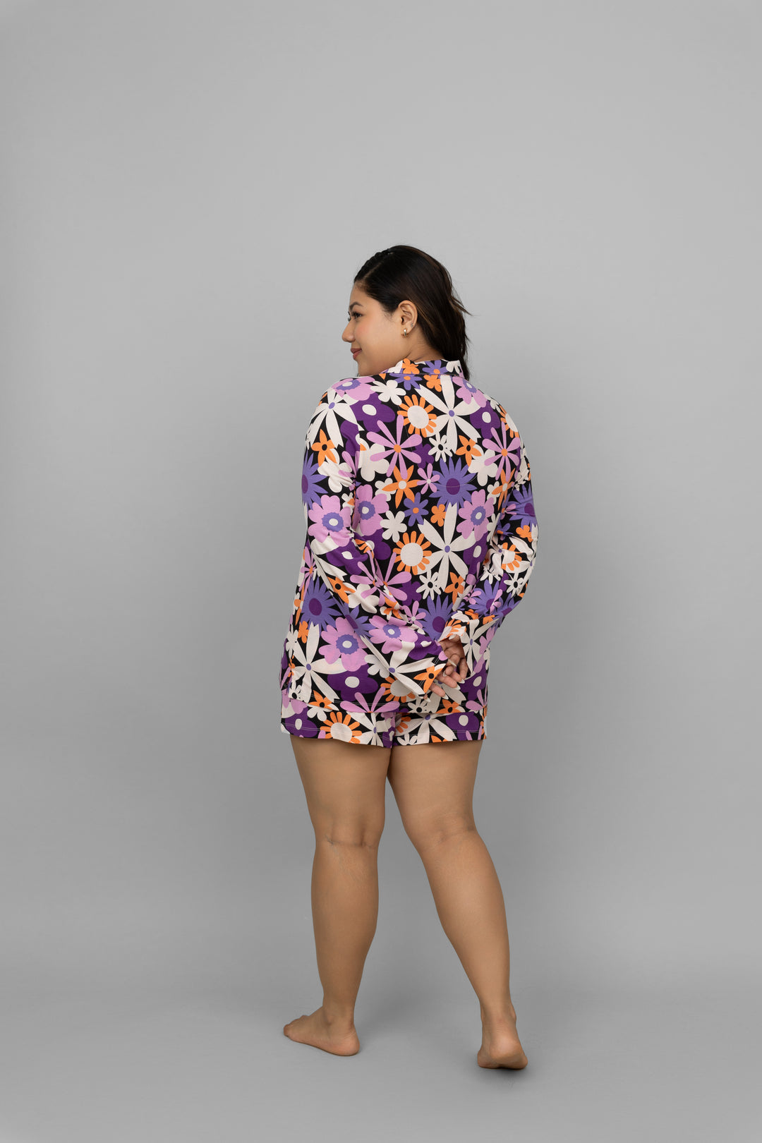 Woman wearing vibrant floral shorts and matching top, showcasing stylish summer fashion.