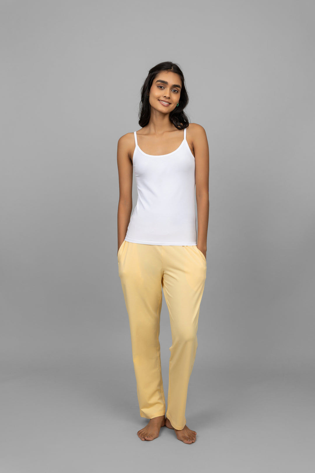 Model wearing a white vest with yellow pants against a gray background.