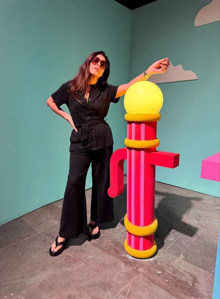 Stylish woman in black outfit next to colorful props.