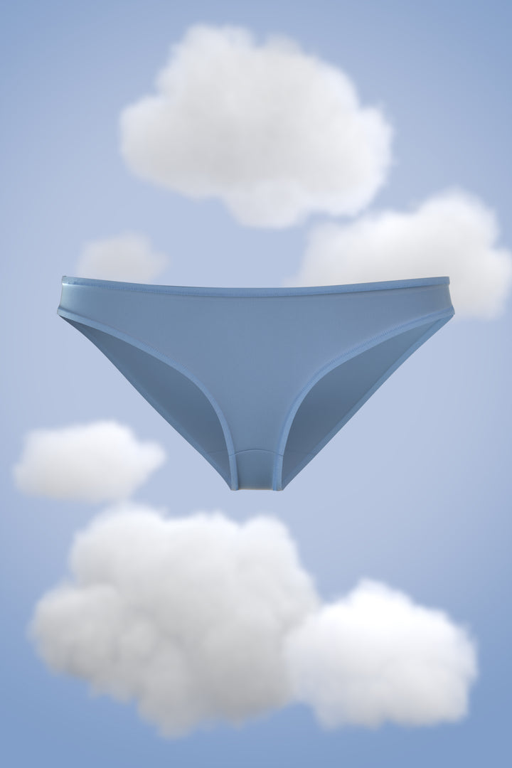 Supima Bikini Nessies in soft blue against a cloudy sky backdrop.