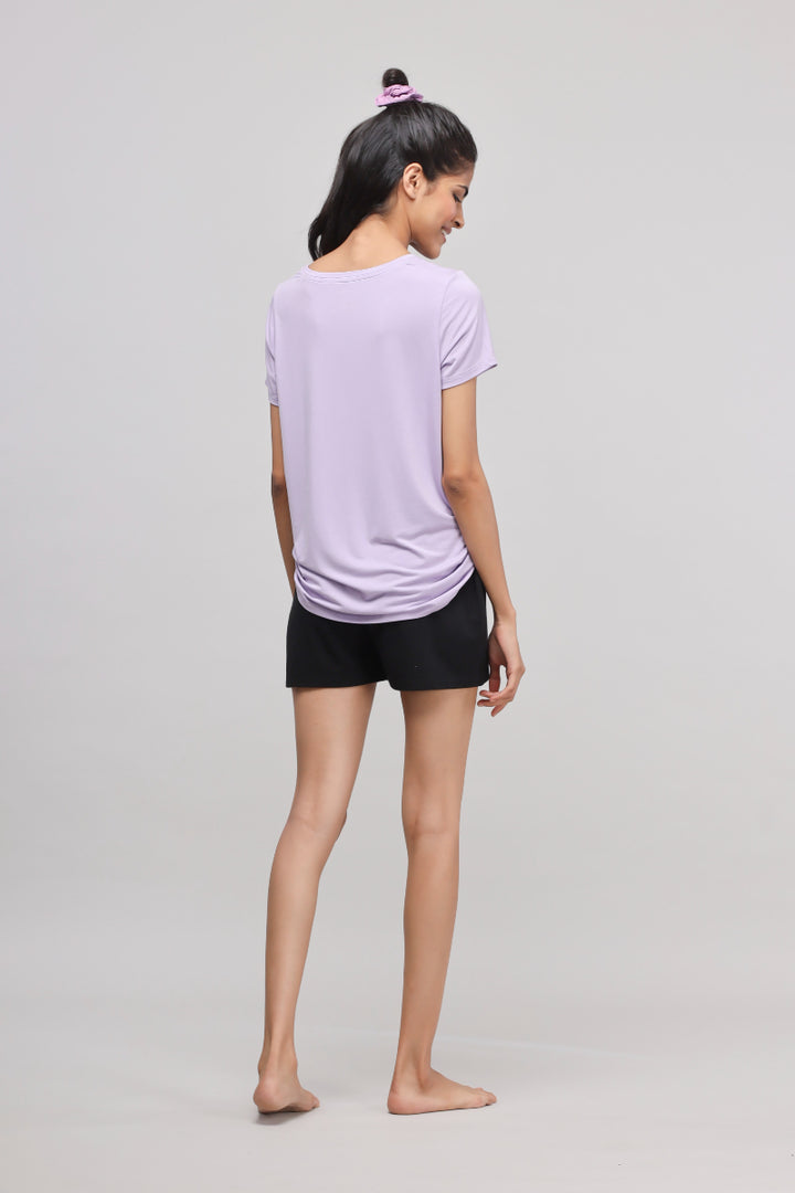 Woman wearing purple shirt and black shorts from Equality Shorts Set.
