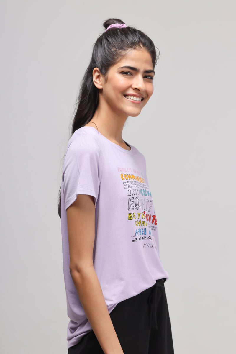 Smiling woman wearing an Equality Purple Top with colorful graphic design.
