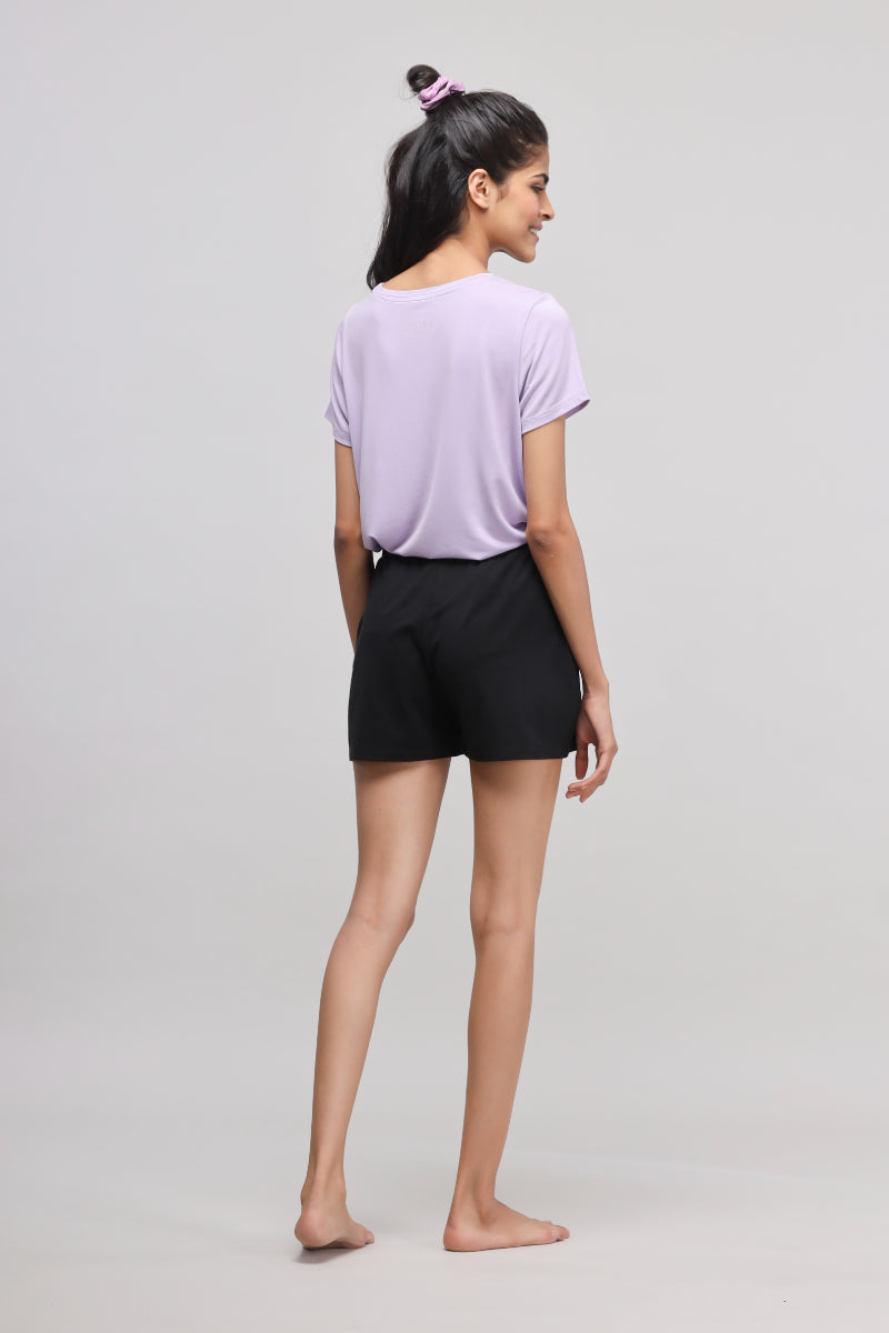 Model wearing stretchy black Supima® shorts and purple top, showcasing casual style.