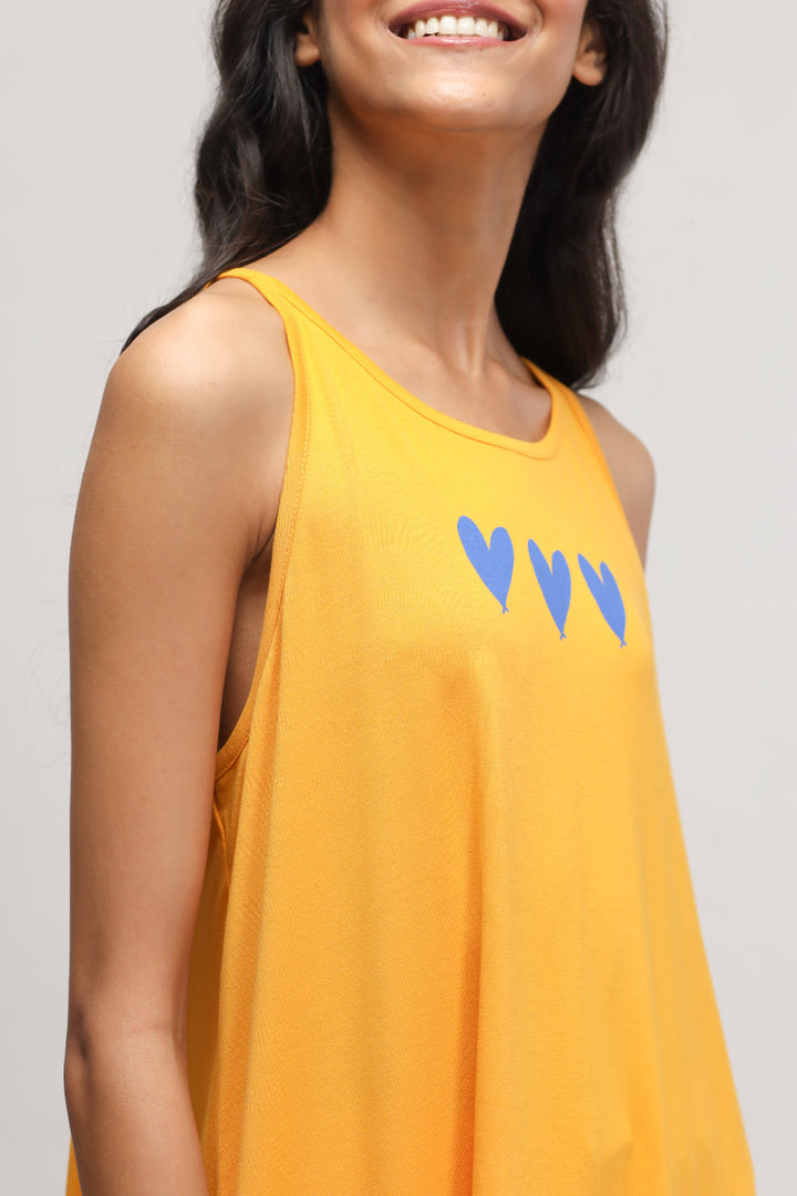 Model wearing bright yellow Butterfly Mango Tank Top with blue heart design.