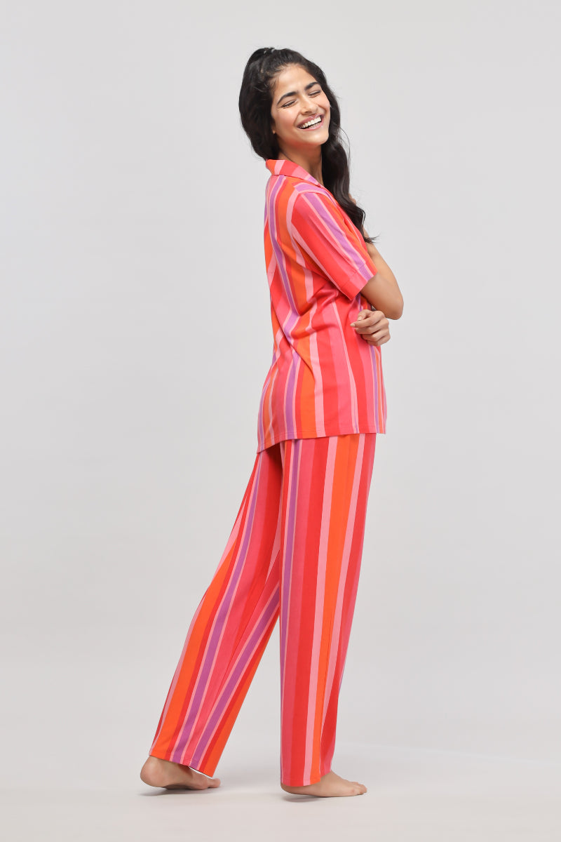 Smiling woman in a vibrant red striped top and pants.
