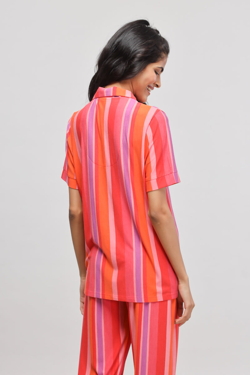 Model showcasing a vibrant red striped top, back view.