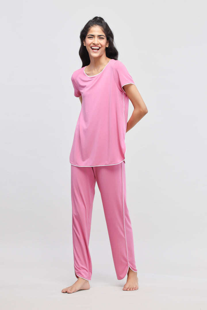 Rose pink pajamas with white piping, model displaying cheerful look.