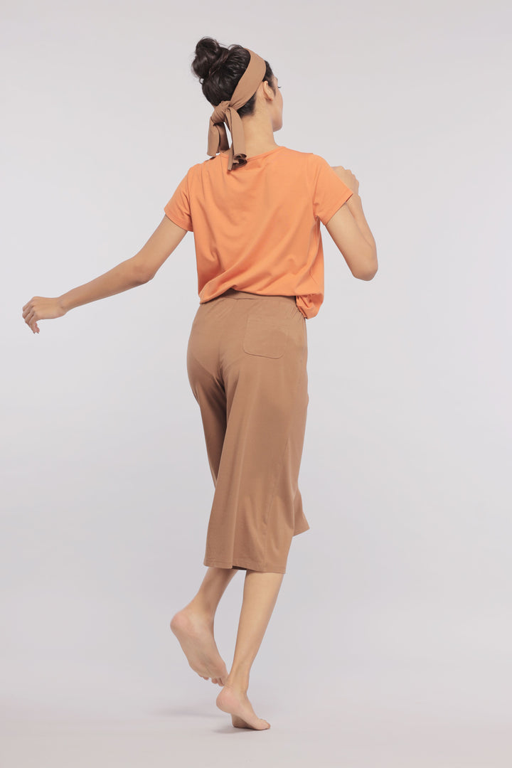 Model wearing Golden Ochre Supima V Neck Tee with brown culottes.