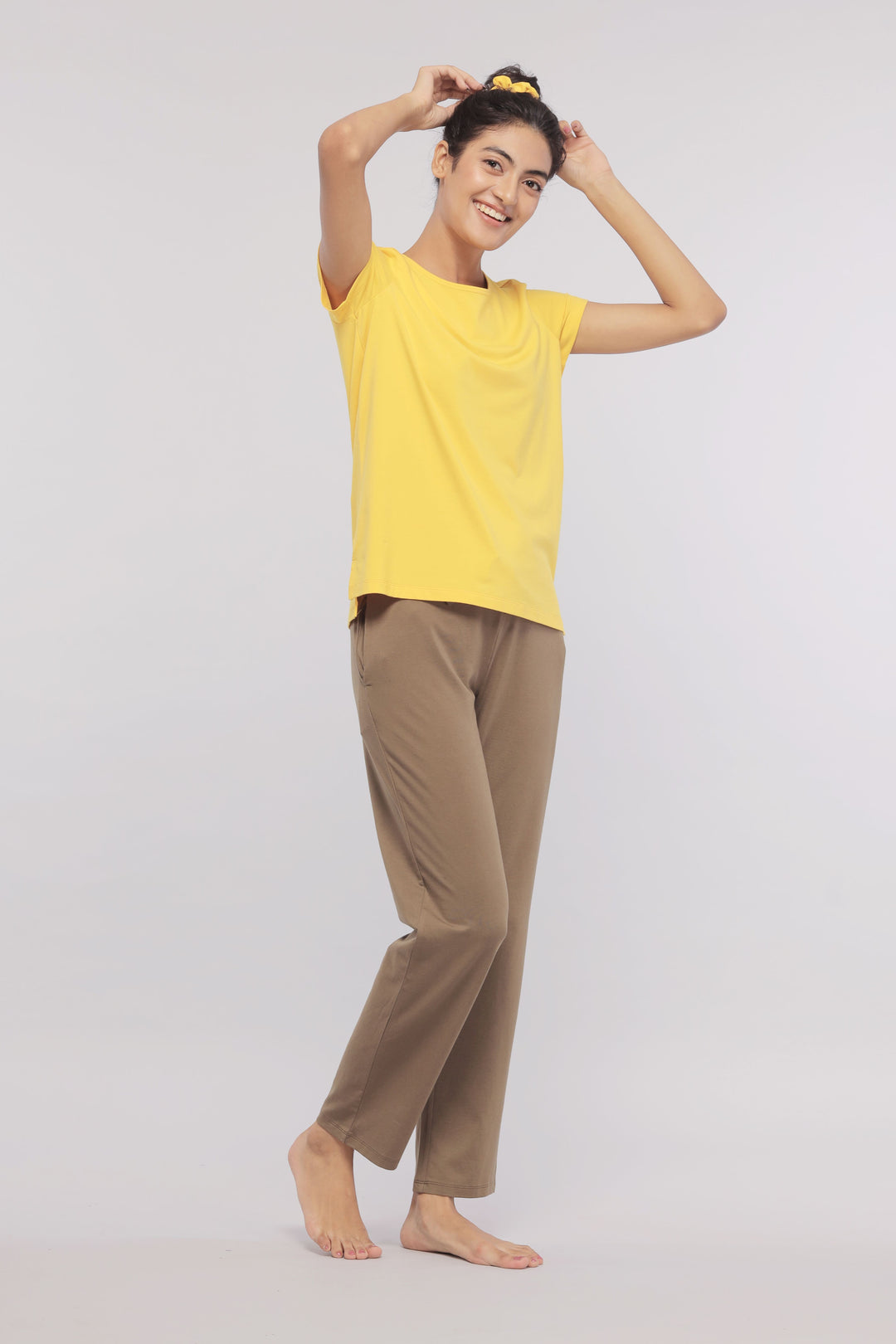 Smiling woman in yellow shirt and brown lounge pants.