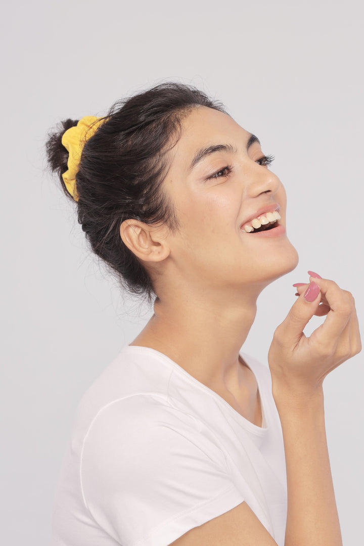 Woman smiling in a white Supima® tee with yellow hair tie.