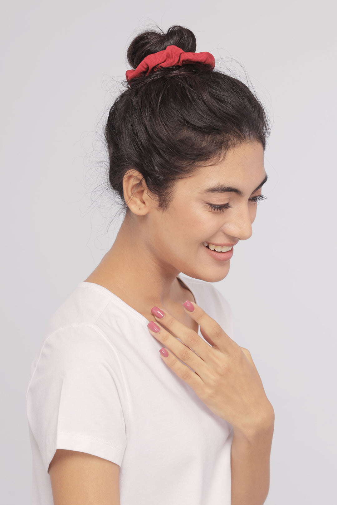 Woman wearing a white Supima® tee, smiling with red scrunchie.