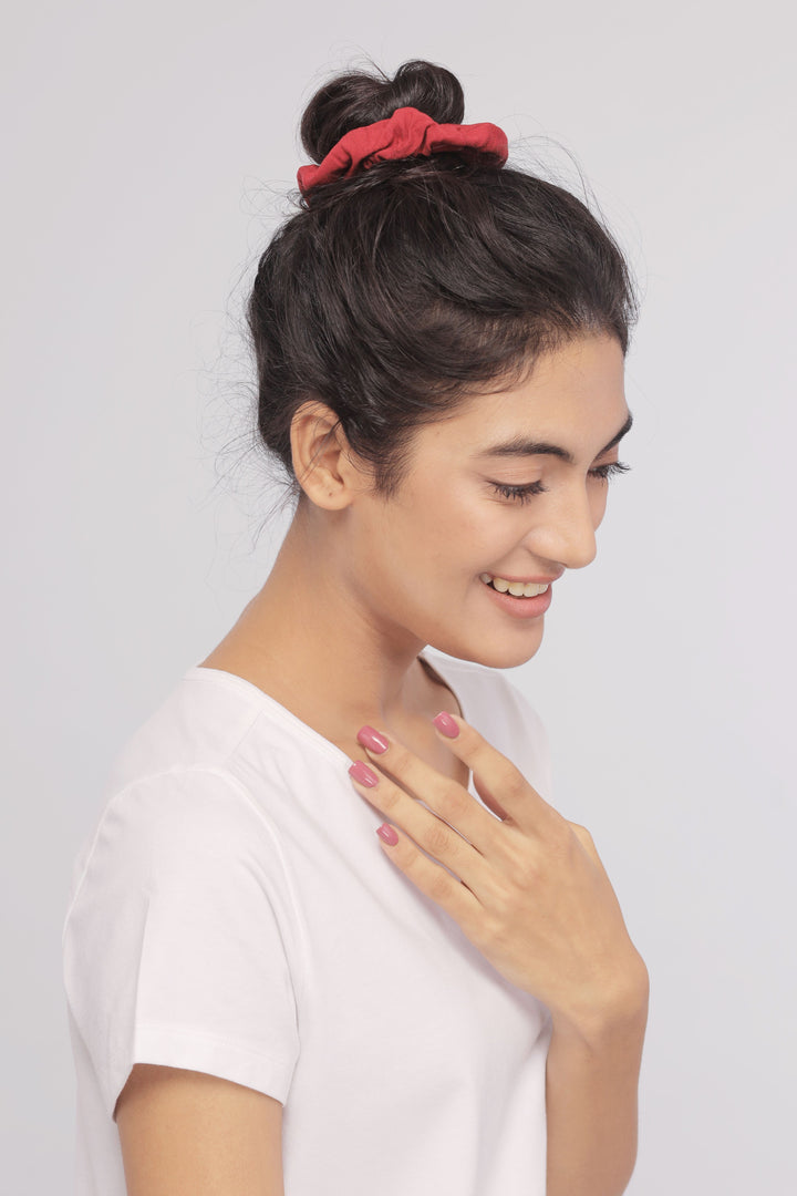 Woman wearing a white Supima® tee, smiling with red scrunchie.