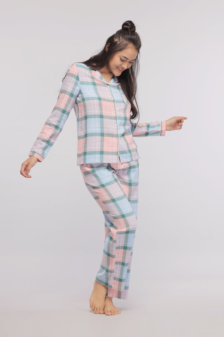 Happy woman in plaid flannel pajamas smiling and posing.