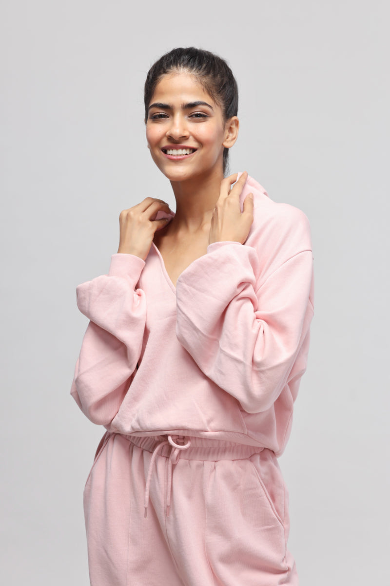 Woman wearing a pink terry hoodie, smiling against a neutral background.