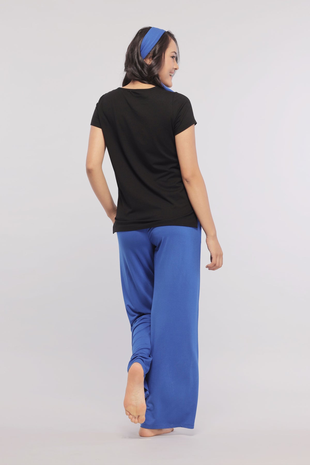 Black Supima® women's tee paired with blue pants, model from behind.