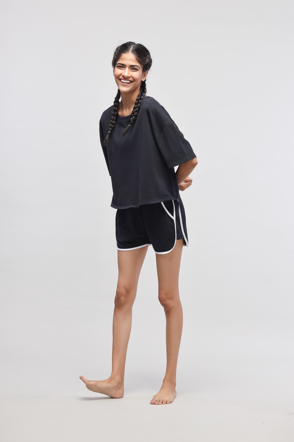 Boxy black cotton top paired with shorts, model smiling.