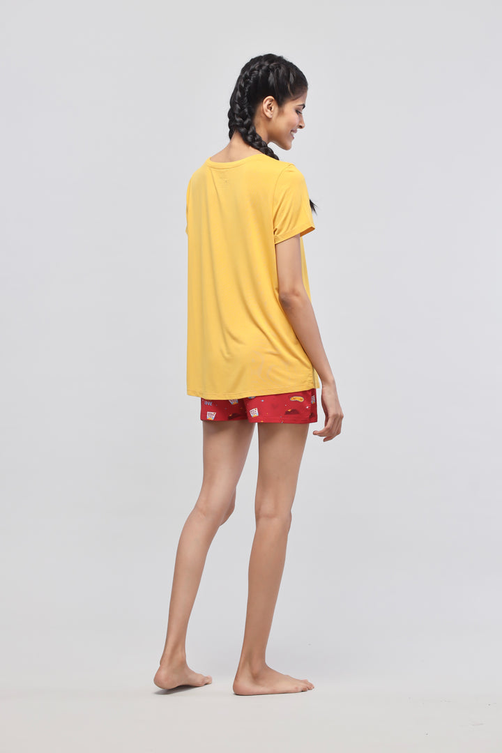 Young woman in yellow self-love top and red shorts.