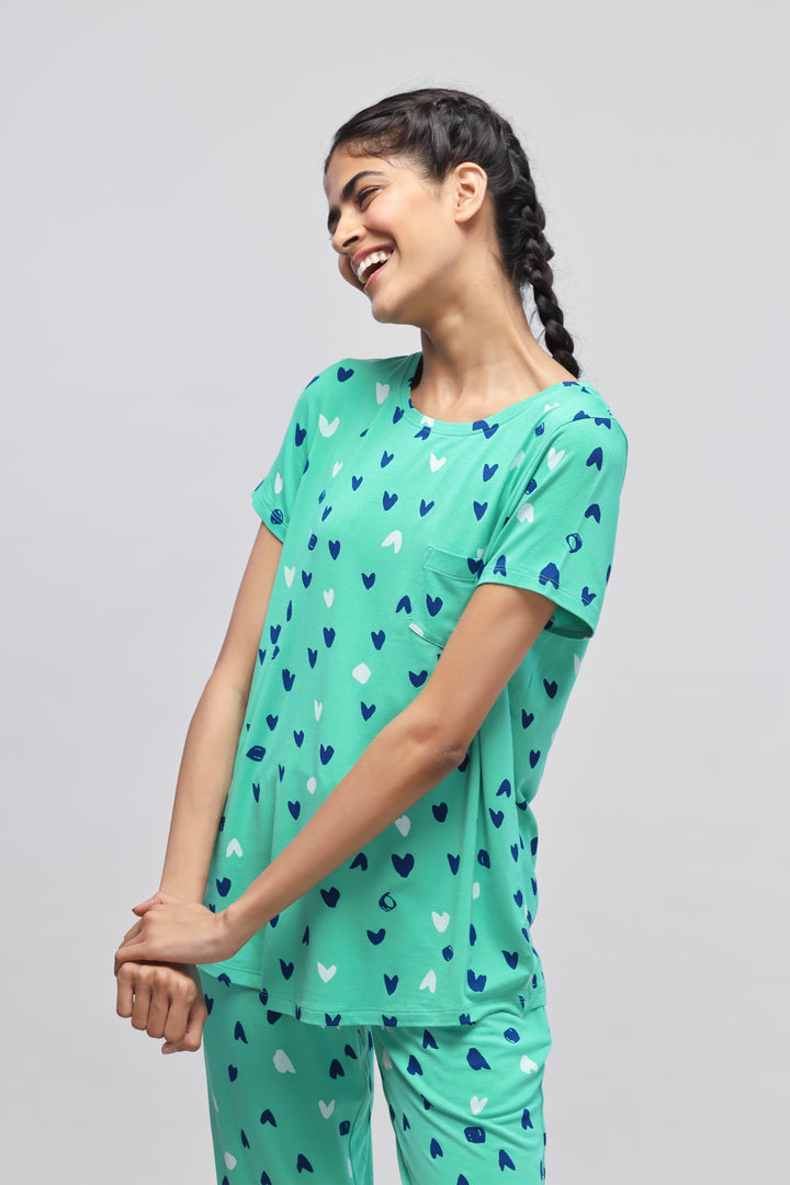 Smiling woman in heart-patterned green Heartsy Top.