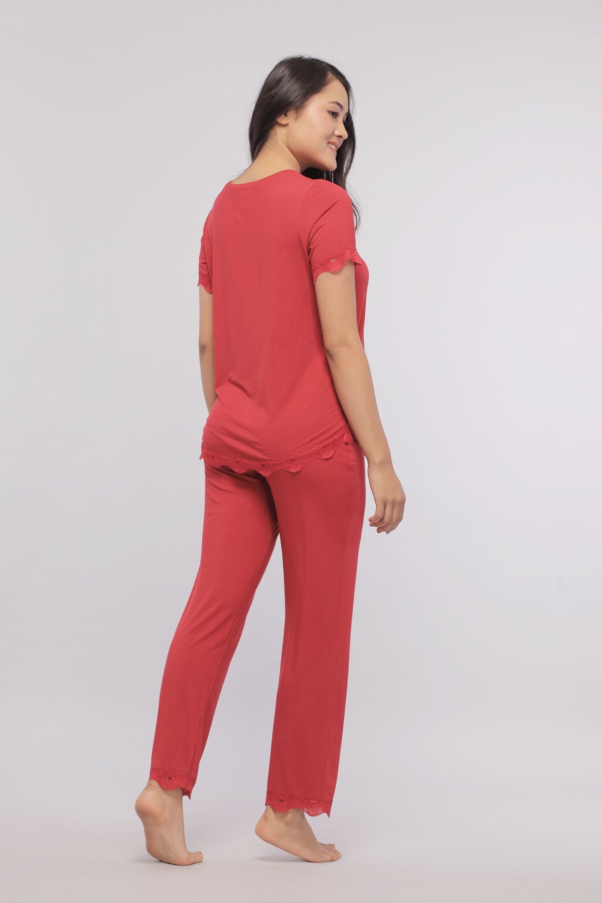 Elegant woman wearing a romantic red lace top and matching pants.