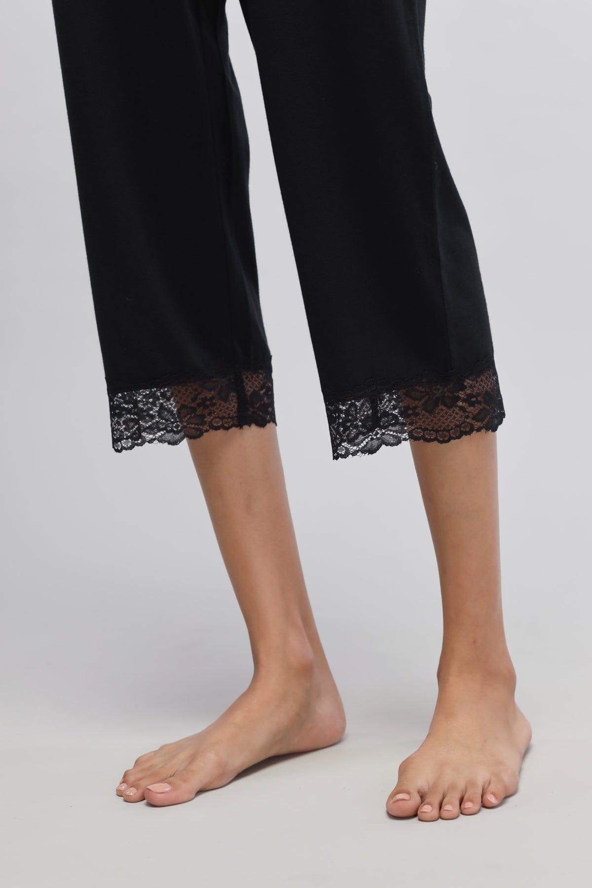 Delicate black lace capri pants with intricate lace detailing.