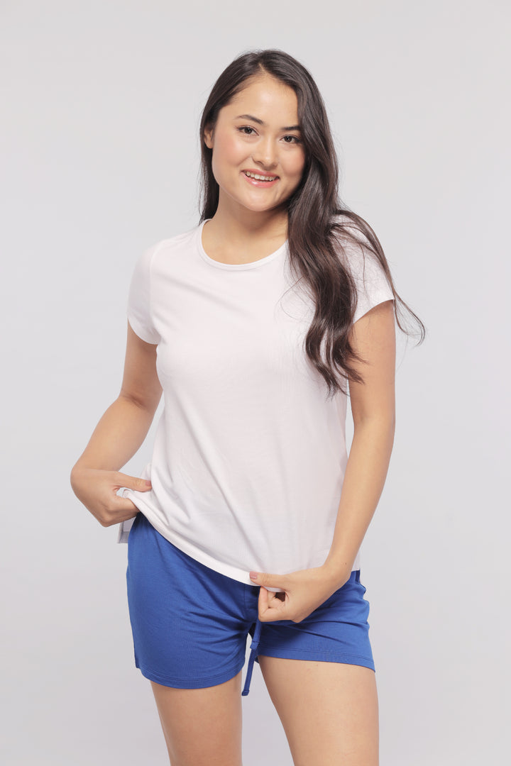 Model wearing a white monochrome shorts set with blue shorts.