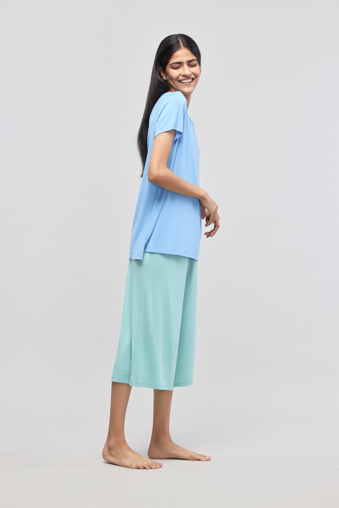 Woman wearing Aqua Culottes with blue top, smiling, casual fashion.