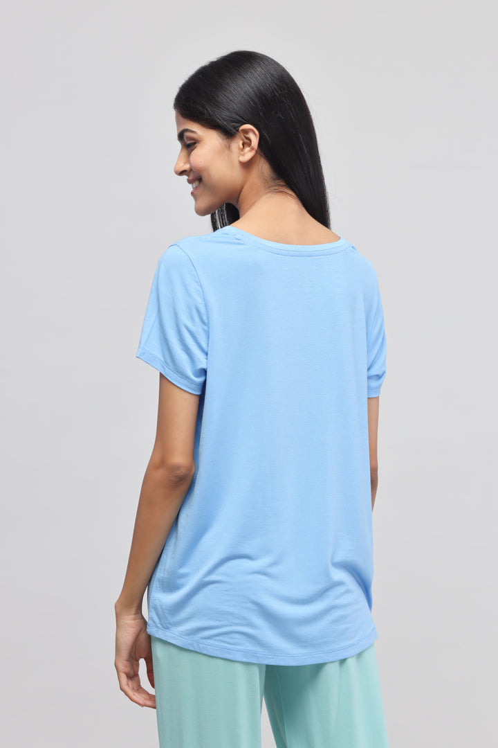 Woman wearing a summer blue round-neck top with casual pants.