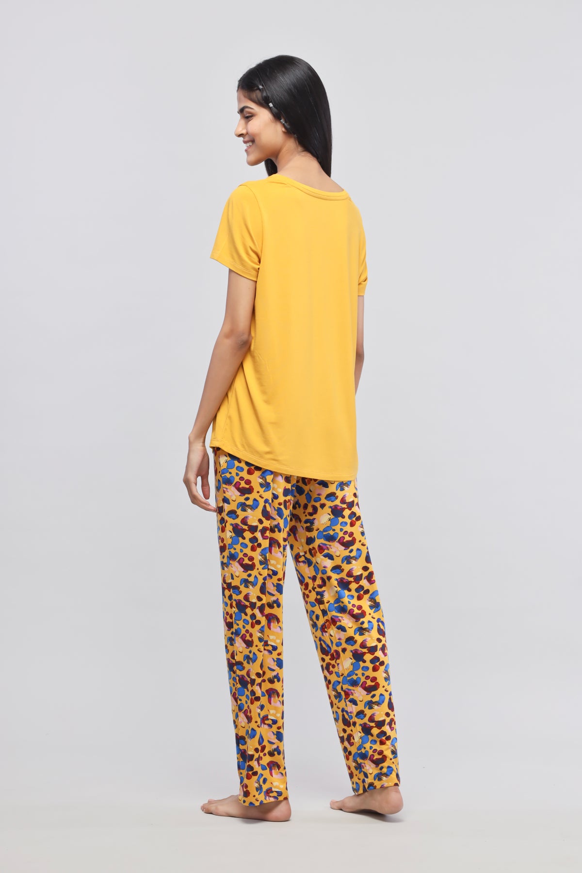Woman in yellow Safari Modal Pajamas with colorful patterned pants.