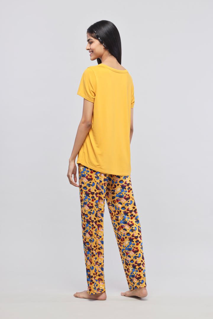 Woman in yellow Safari Modal Pajamas with colorful patterned pants.