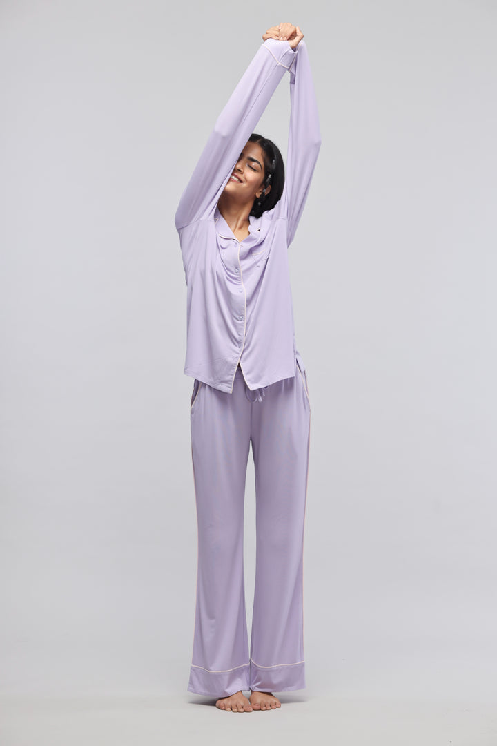 Model stretching in stylish lavender piping pajamas against a neutral background.