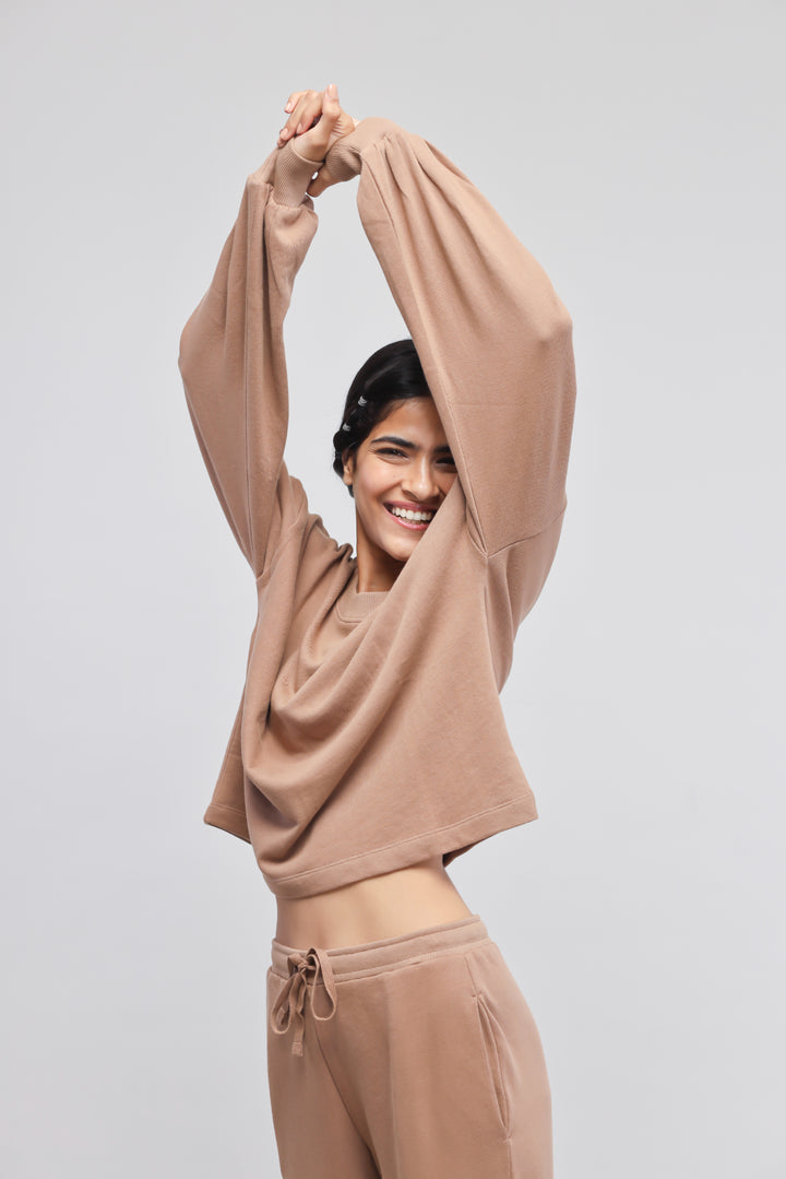 Brown terry puffed sweatshirt styled with matching sweatpants, model smiling.