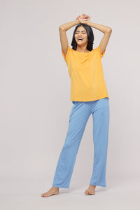 Smiling woman in cozy blue straight lounge set and yellow top.