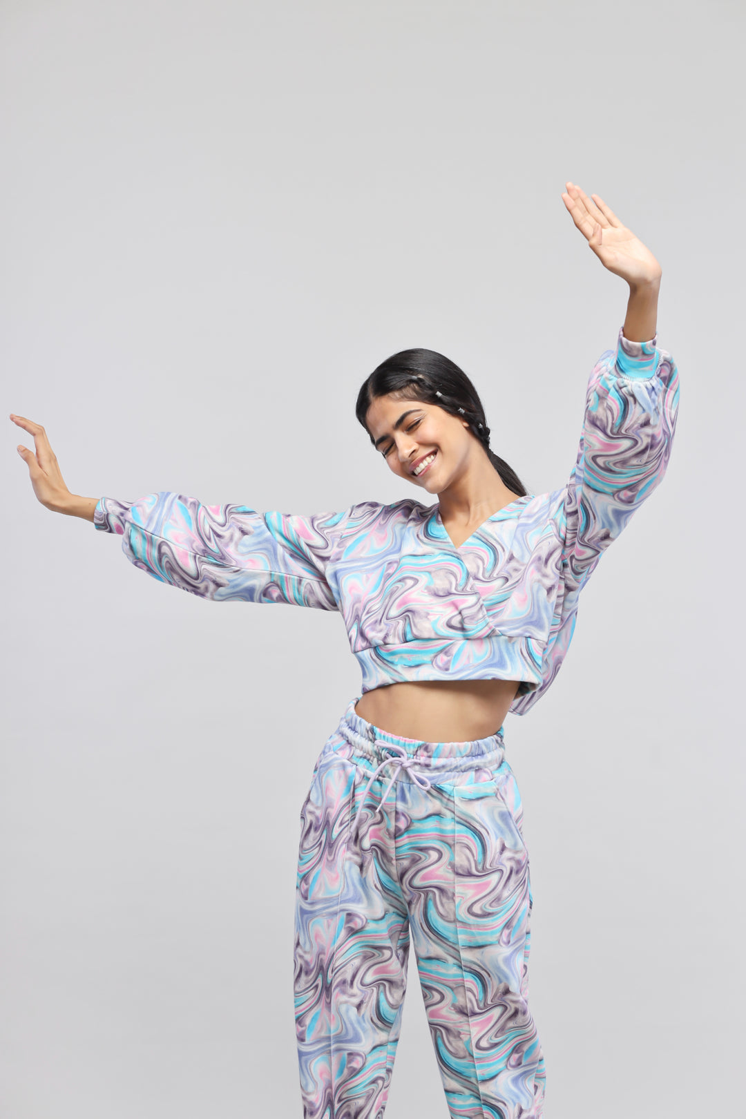 Smiling woman wearing Fluid Terry Hoodie and matching pants with colorful swirl pattern.
