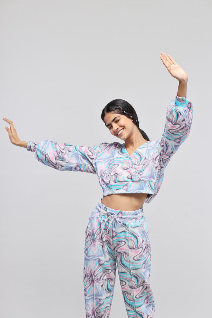 Smiling woman wearing Fluid Terry Hoodie and matching pants with colorful swirl pattern.