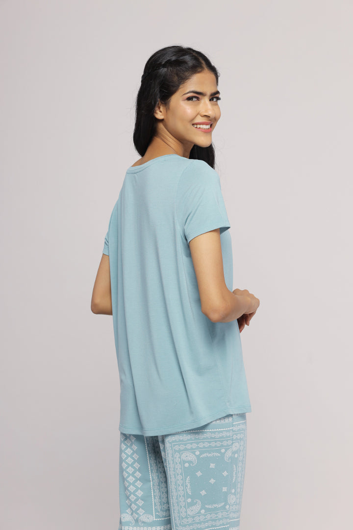 Misty teal top worn with patterned trousers, showcasing a stylish look.