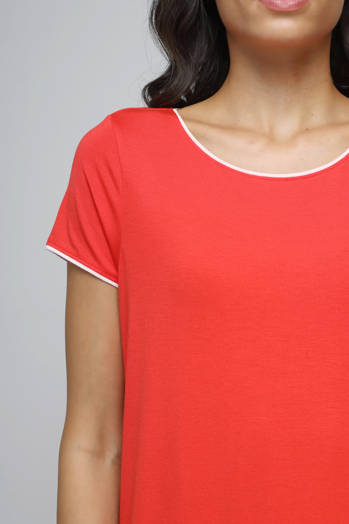 Close-up of woman wearing vibrant red top with white piping detail.