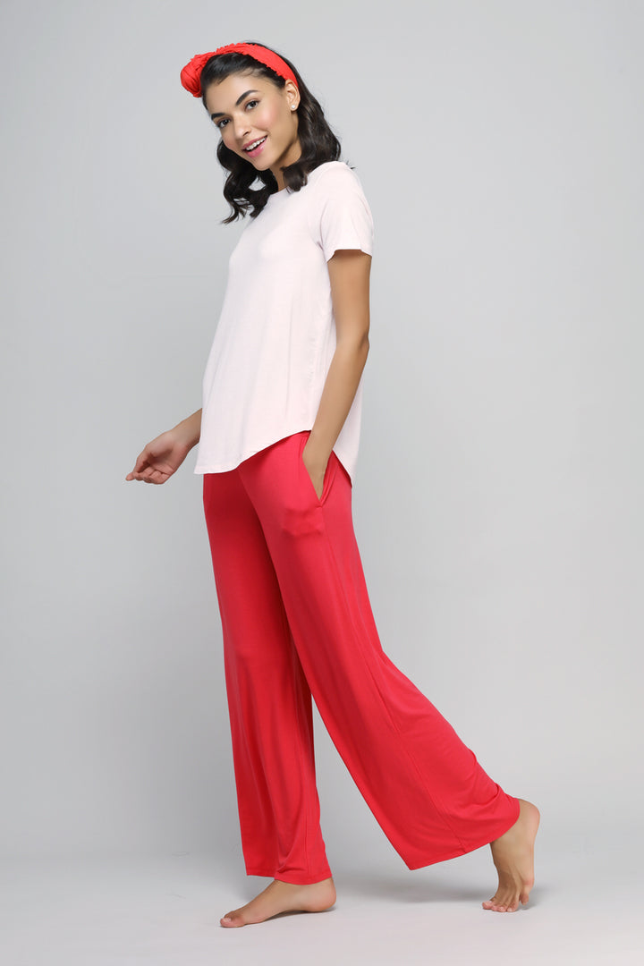 Woman in blush top and red pants, stylish casual outfit.