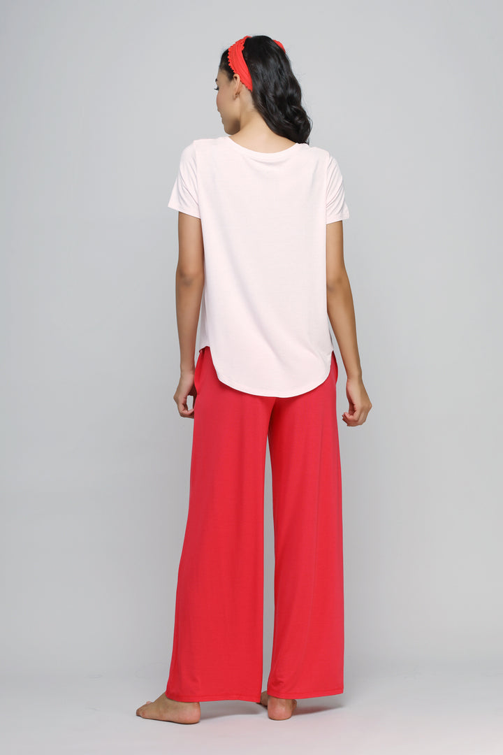 Model wearing delicate blush top with stylish red pants.